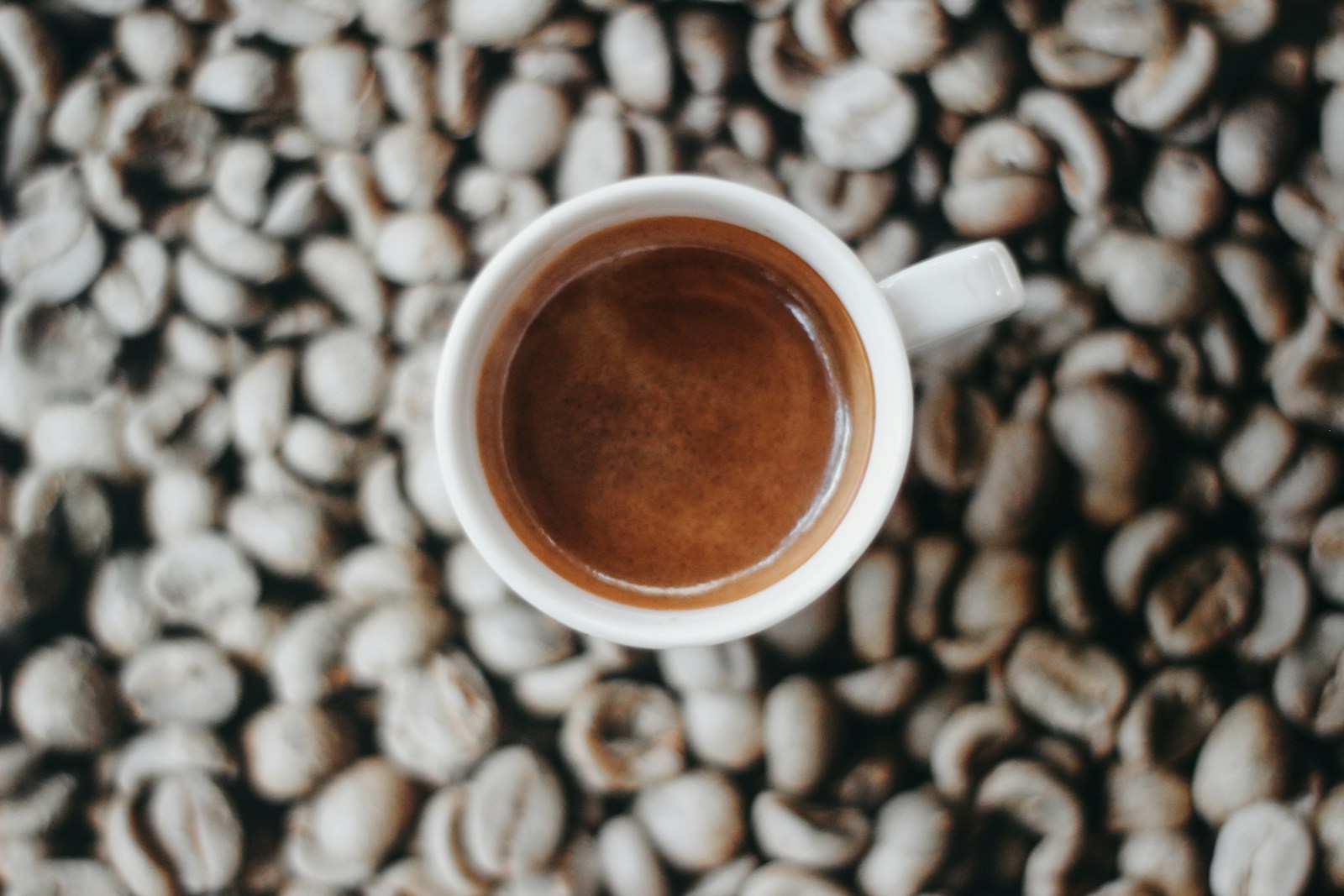 Tách espresso đặt trên nền hạt cà phê rang